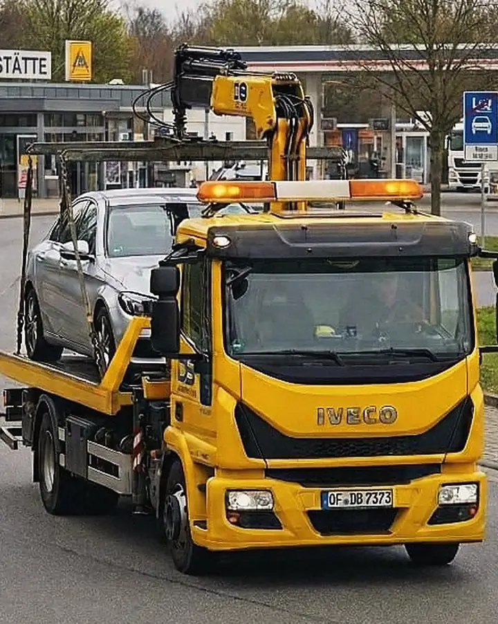 Gelber Iveco-Abschleppwagen von vorne mit verladenem Auto